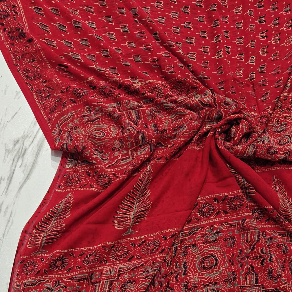 Red chiffon saree with intricate black patterns on a white background