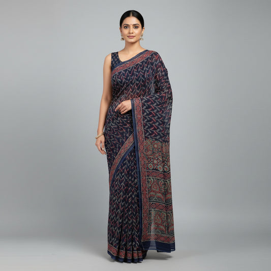 A navy blue block-print cotton saree with intricate red, green, and gold patterns, laid out on a light gray textured surface. A white label in the bottom-left corner reads 'chiffon saree'.