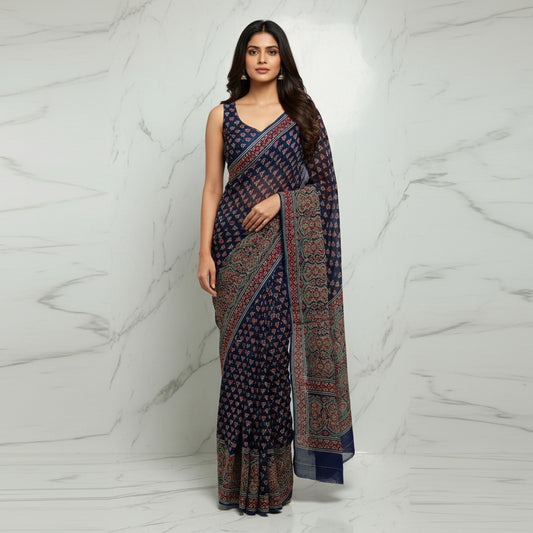 A navy blue chiffon saree with intricate red, beige, and white block-printed patterns and borders, draped on a light marble surface.