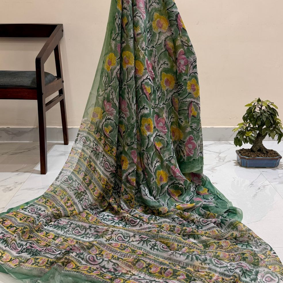 Green floral patterned  draped over a chair with a plant in the background