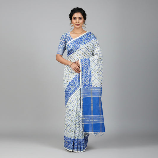 A cream-colored fabric saree or scarf with intricate blue and green geometric patterns, laid flat on a wooden floor.