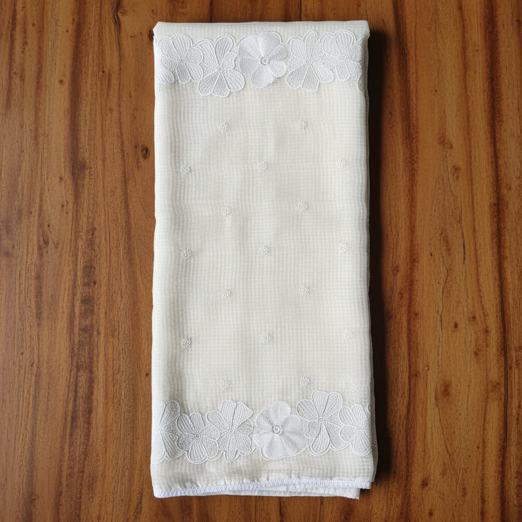 Folded white fabric with lace trim on a tiled floor